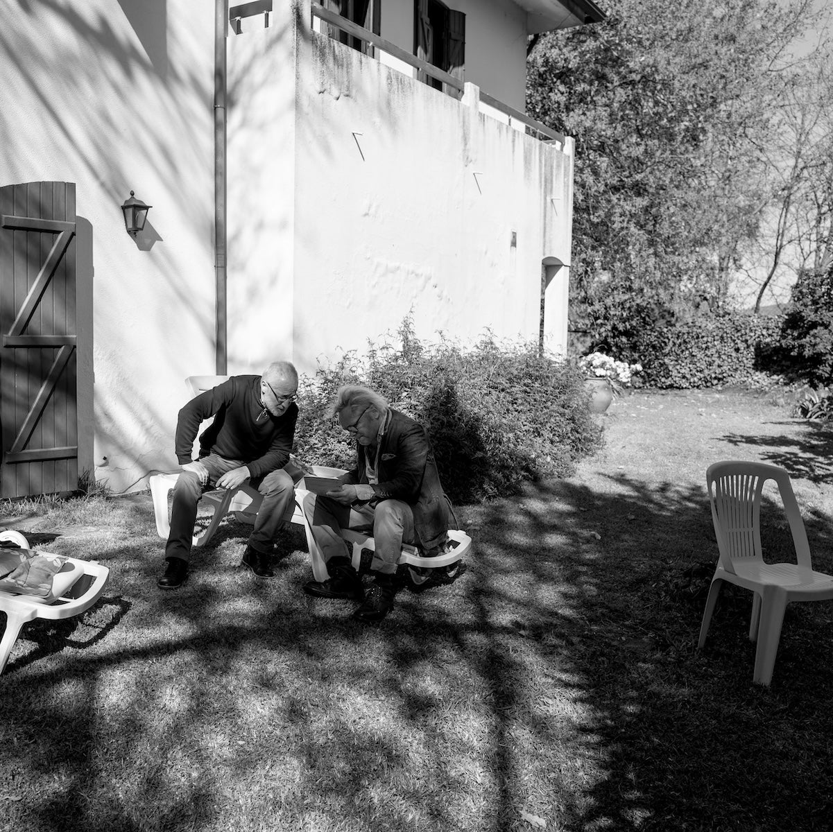 Virgilio Gonçalves and Claes Bondelid sitting on a bench in a garden with a house in the background