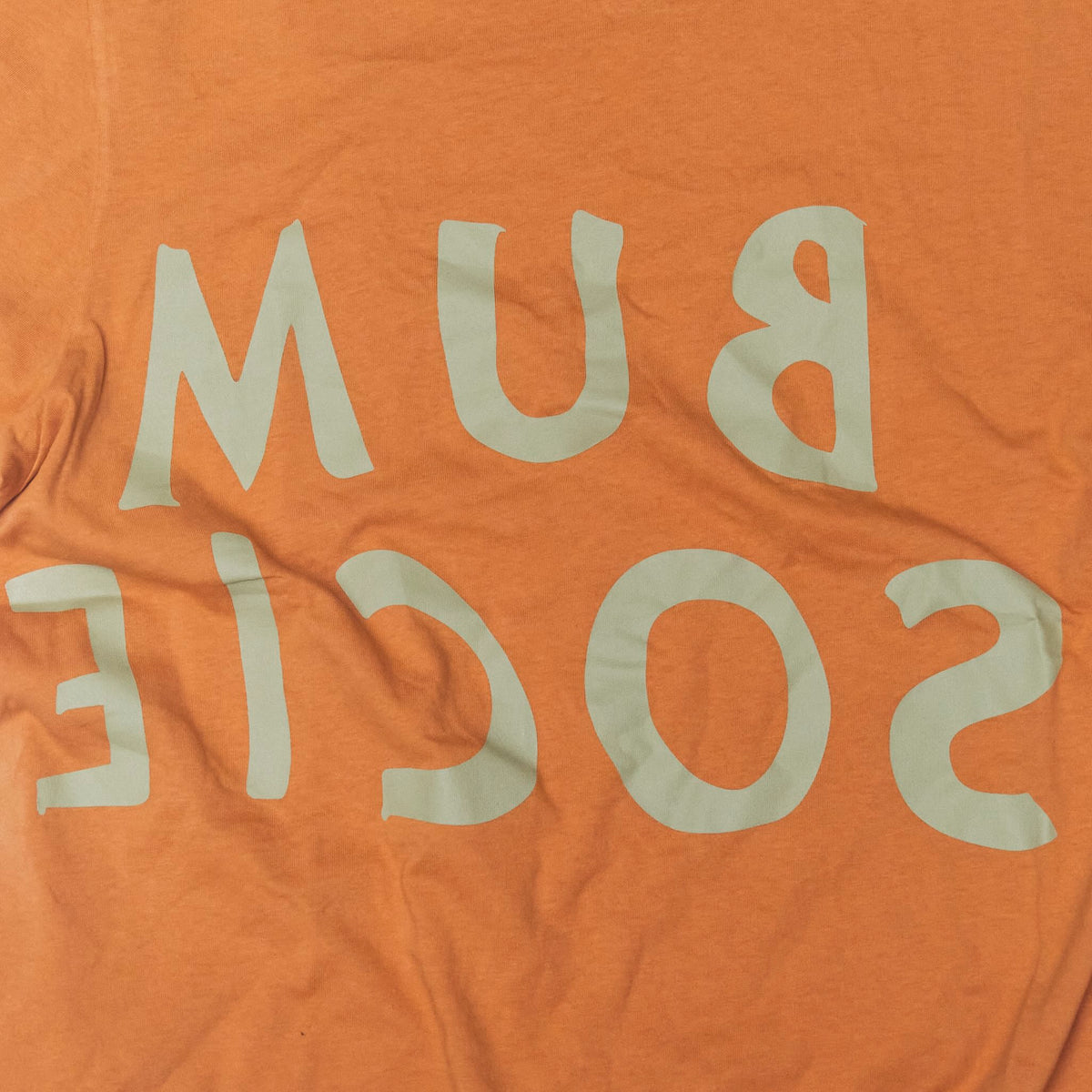 Close up reversed Bum Society logo print color:bs orange