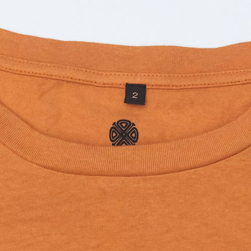 Close-up of a burnt orange garment with Bum Society neck print with four-leaf clover color:bs orange