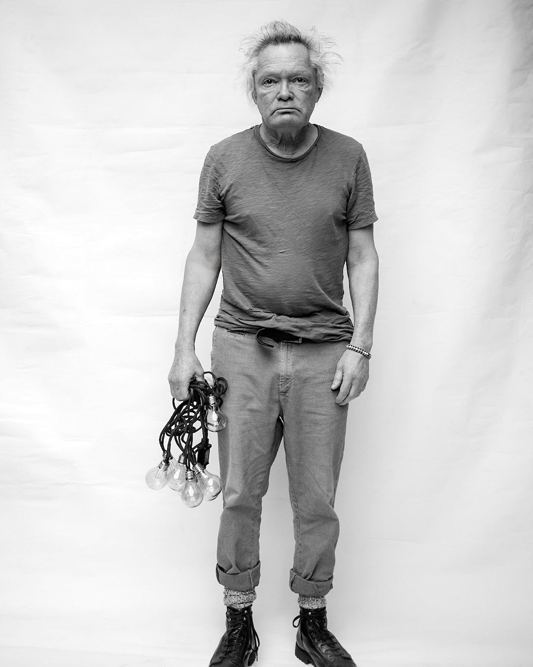 Black and white portrait of Claes Bondelid holding light bulbs against a plain background