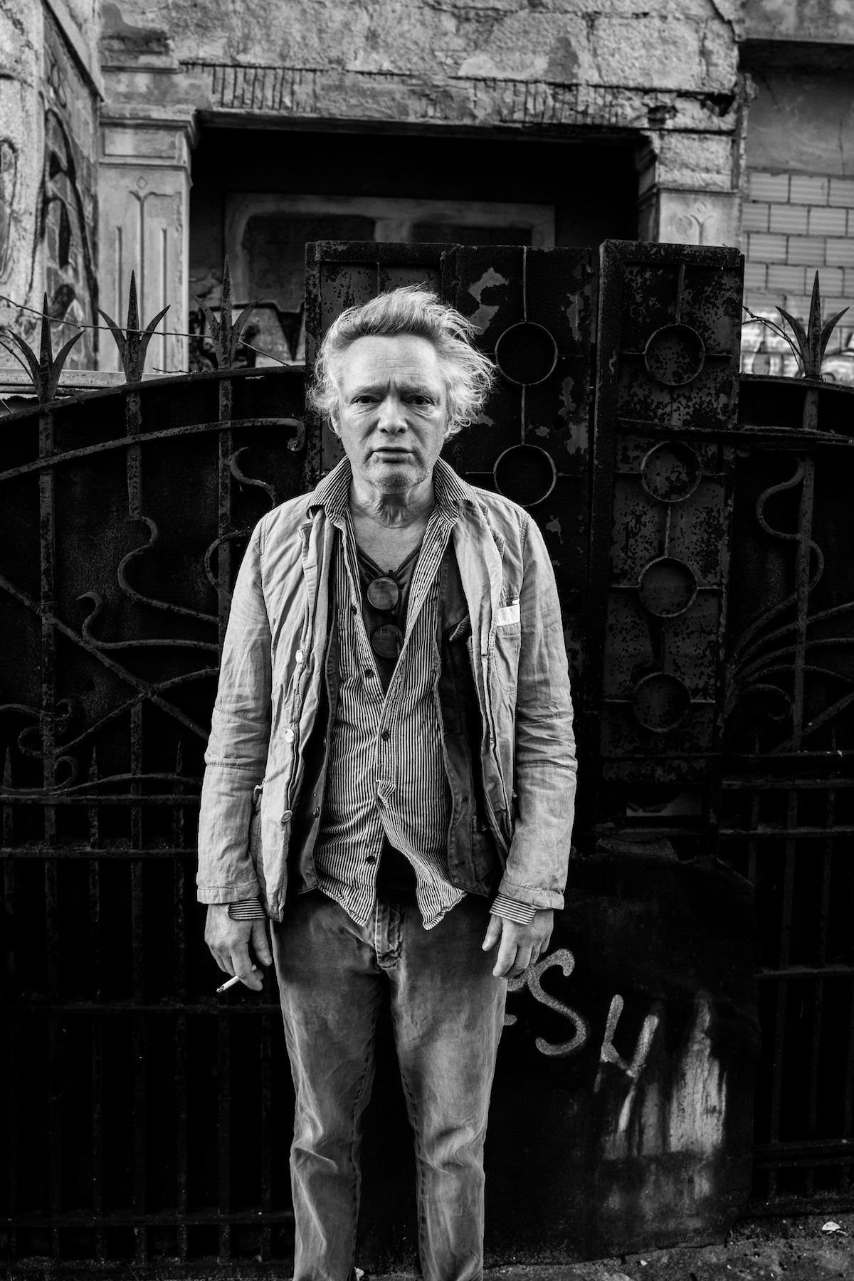 Black and white portrait of Claes Bondelid standing in front of a decorative metal gate in Porto