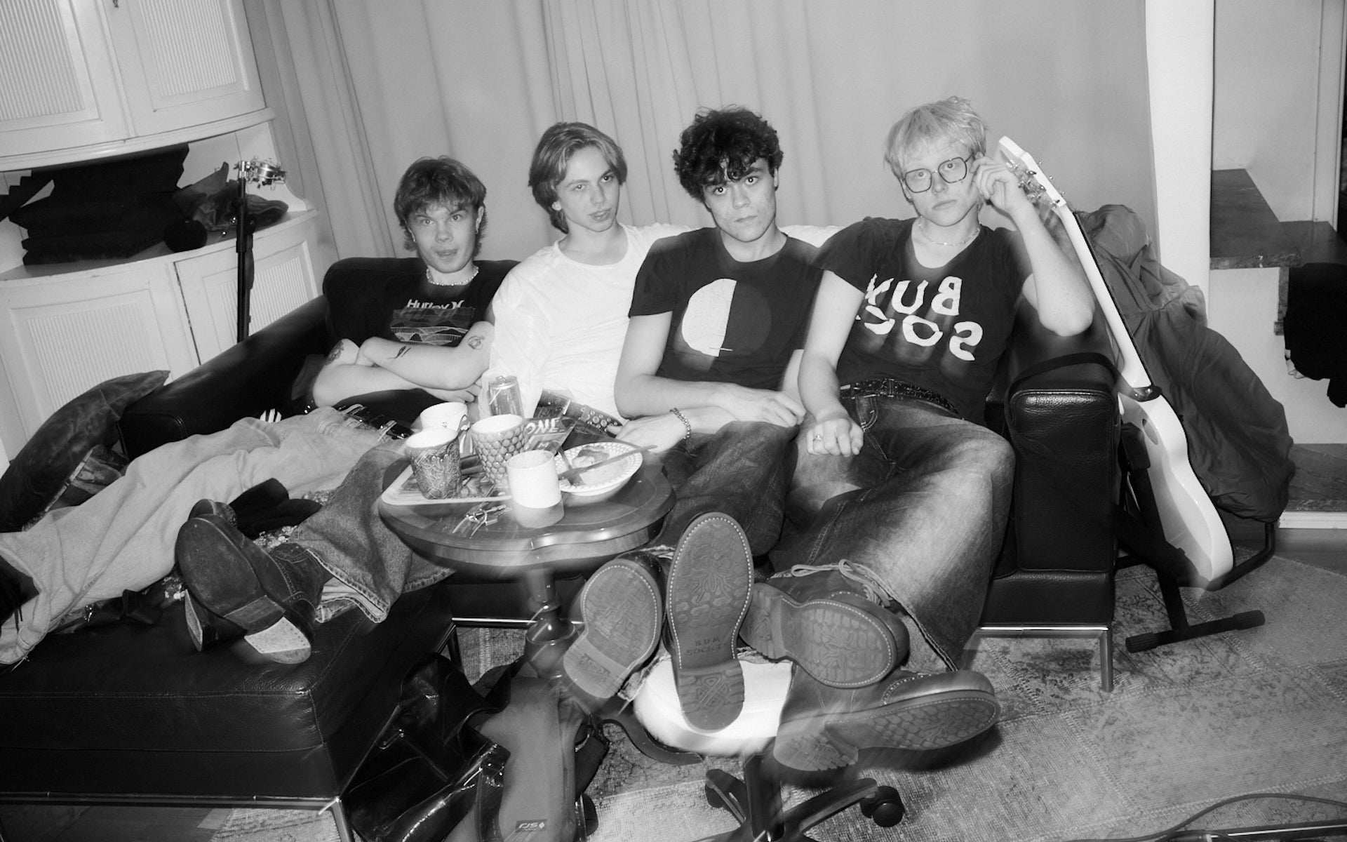 Black and white photo of music band Diset sitting on a couch in their basement studio