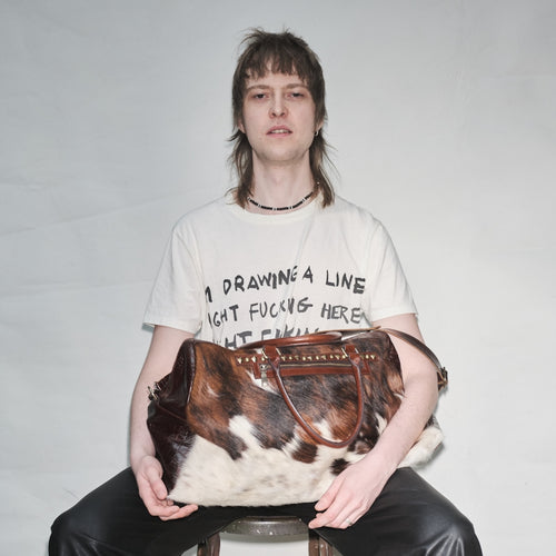 Person holding a pony hair Bum Society duffle bag Dandy Brown against a plain background color:dandy brown, snow