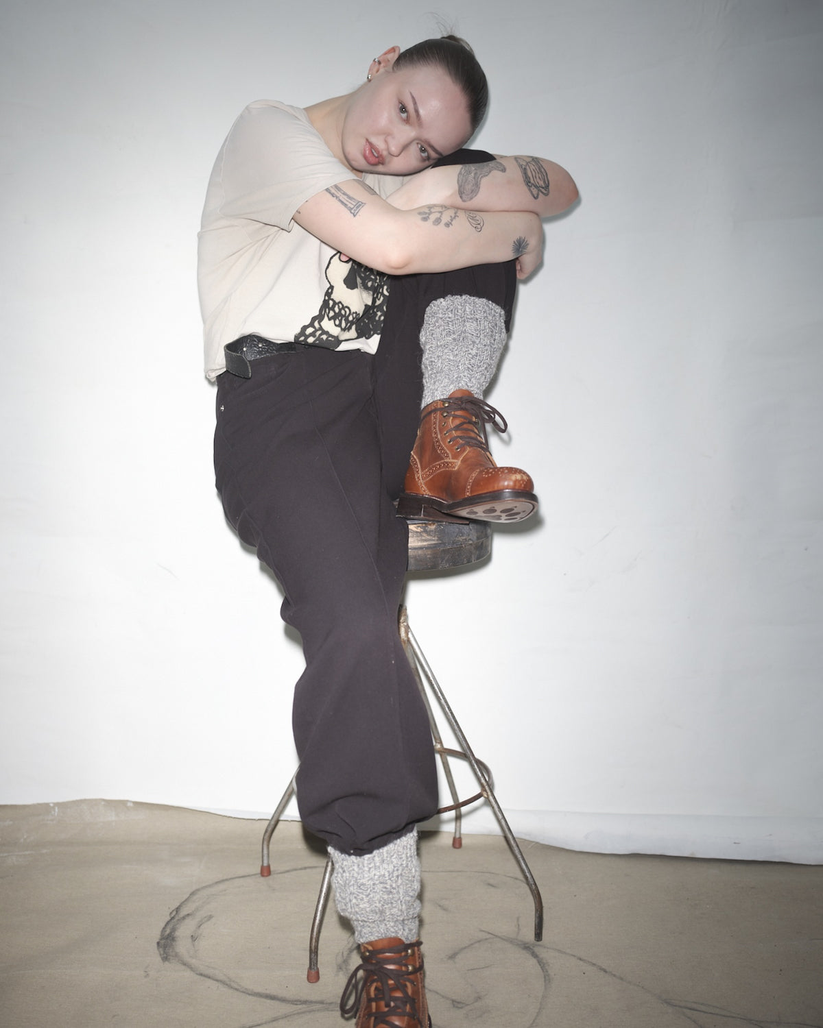 Elsa Lyck sitting on a stool with crossed legs in brown Bum Society boots against a plain background