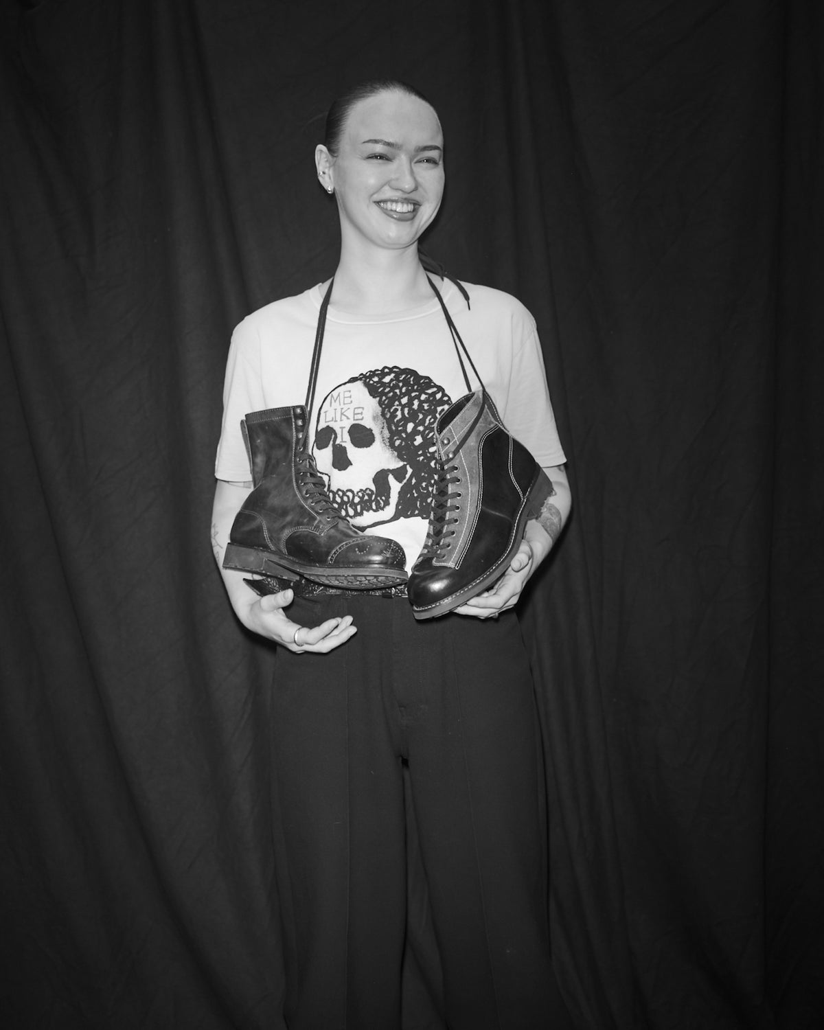 Elsa Lyck holding a pair of Bum Society boots with a Waldersten x Bum Society t-shirt on a dark background