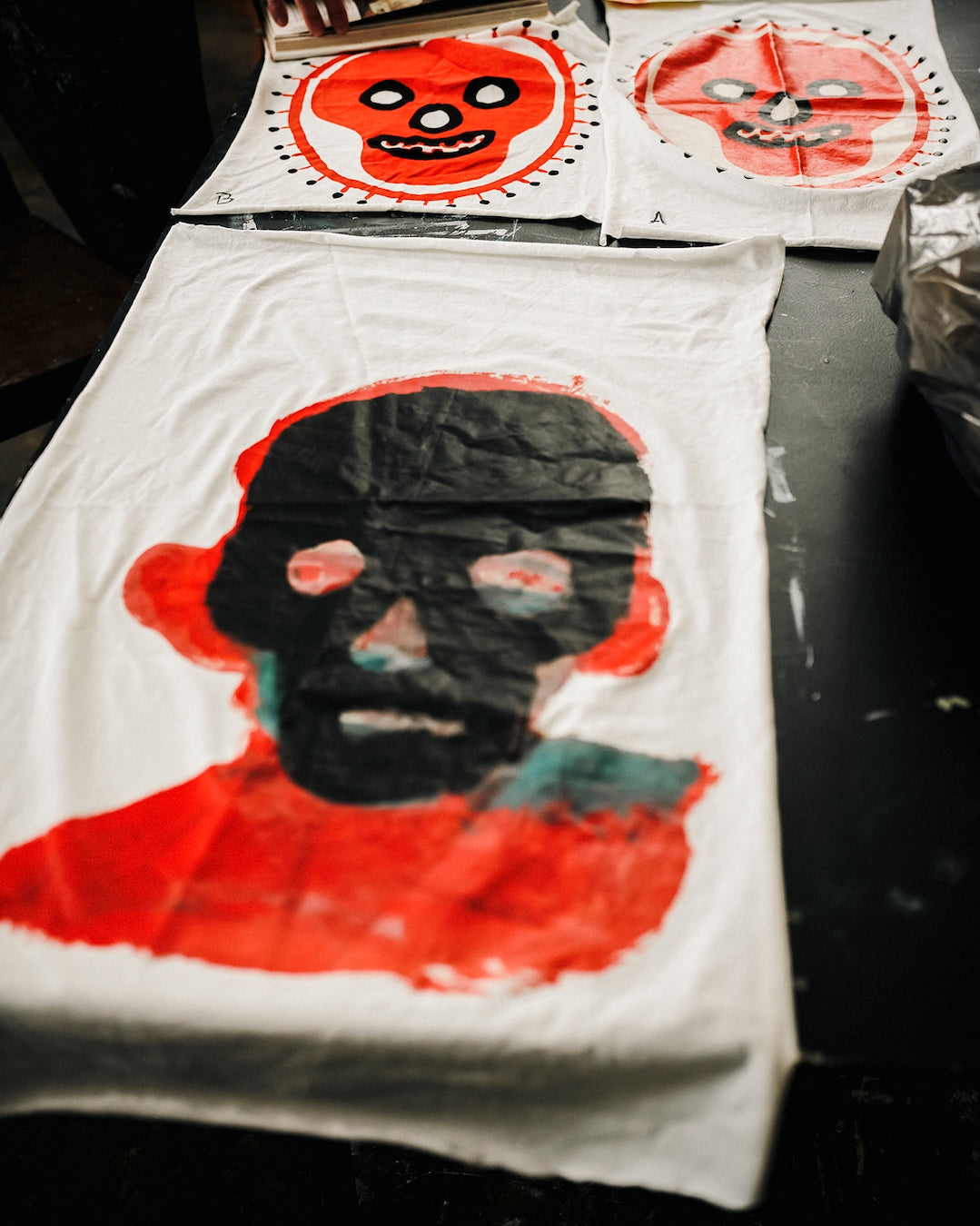 White t-shirt fabric with red and black Waldersten artwork laying on a dark surface