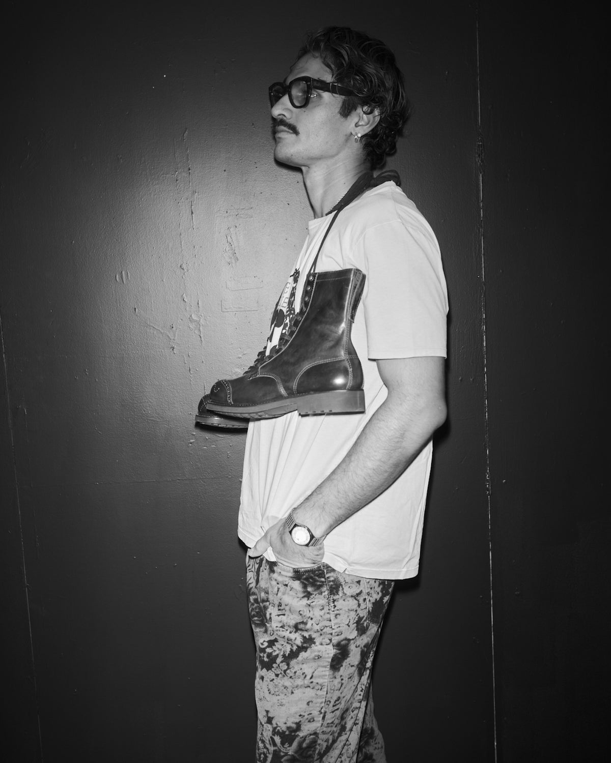 Person holding a pair of boots against a dark background