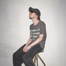 Man sitting on a stool wearing original Waldersten artwork Drawing A Line printed on a Bum Society t-shirt and cap against a plain background color:ink