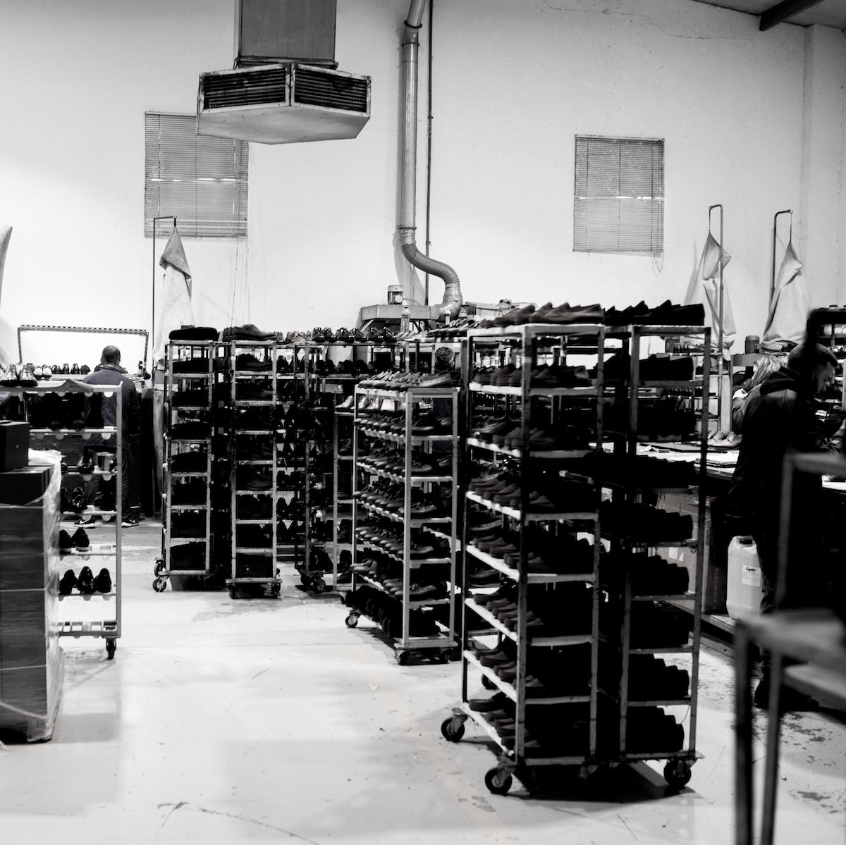 Black and white photograph of boots factory with shelves stocked with lasts