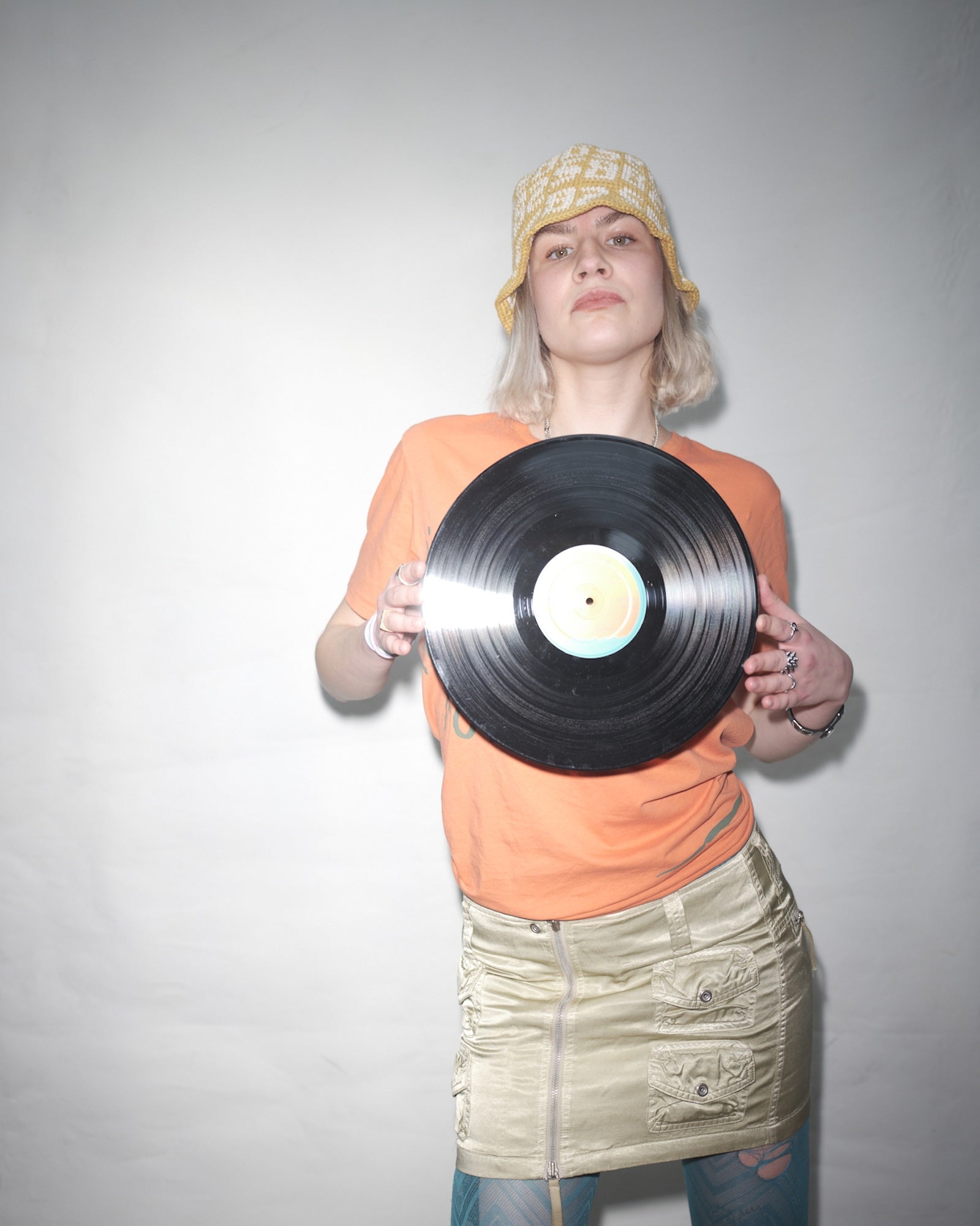 Lydia Halkiewicz holding a vinyl record against a plain background in Vbrani x Bum Society crochet bucket hat