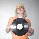 Person holding a vinyl record against a plain background wearing a Bum Society x Vbrani crochet bucket hat color:lucky yellow