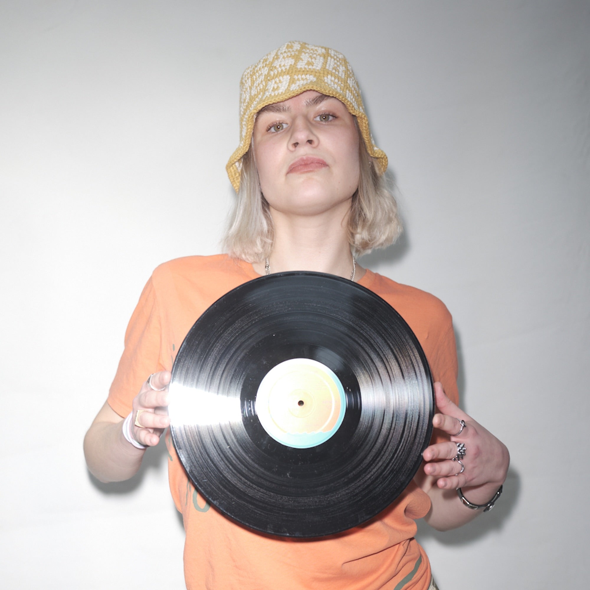 Person holding a vinyl record against a plain background wearing a Bum Society x Vbrani crochet bucket hat color:lucky yellow
