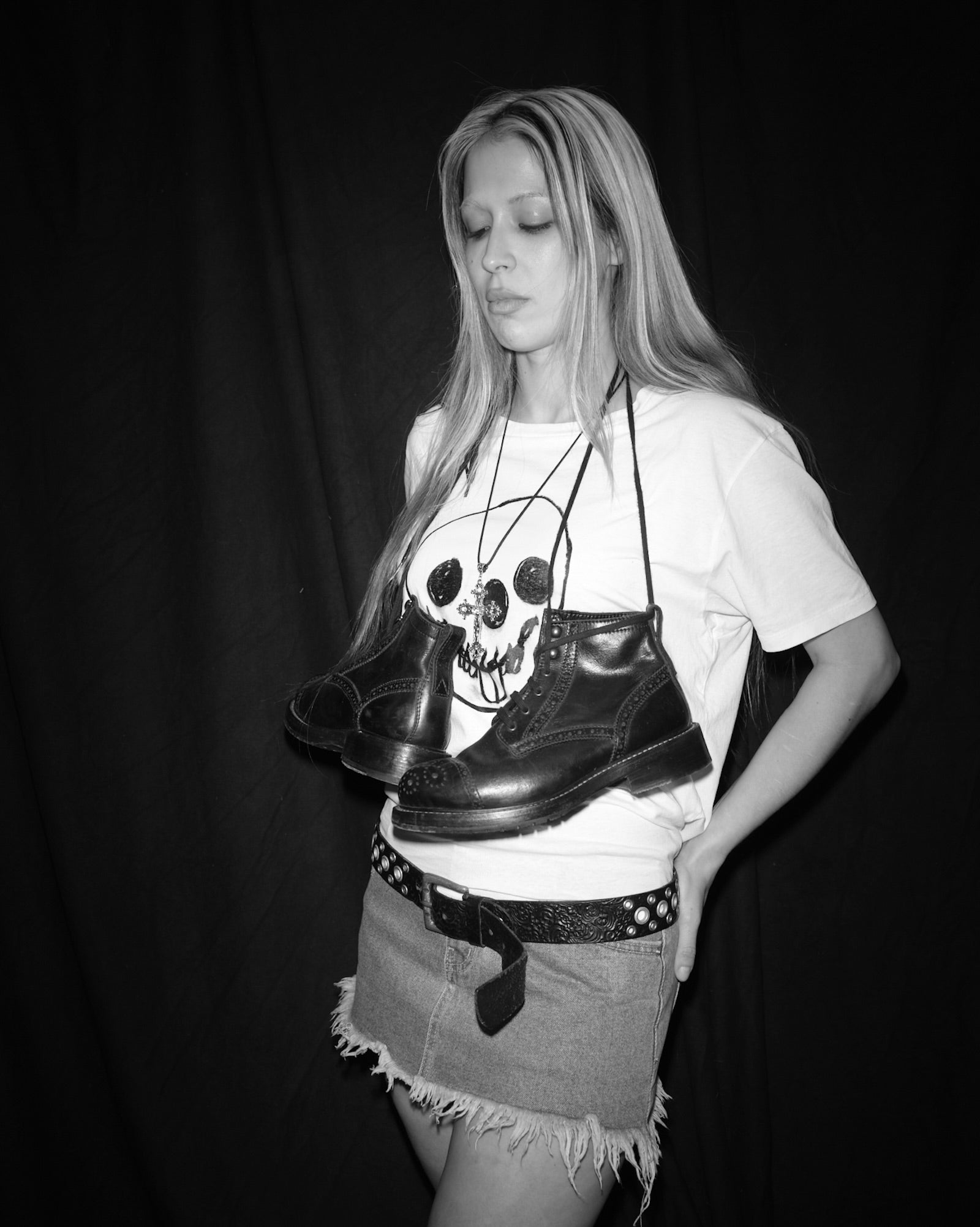 Nena Vadman holding black Bum Society boots against a dark background