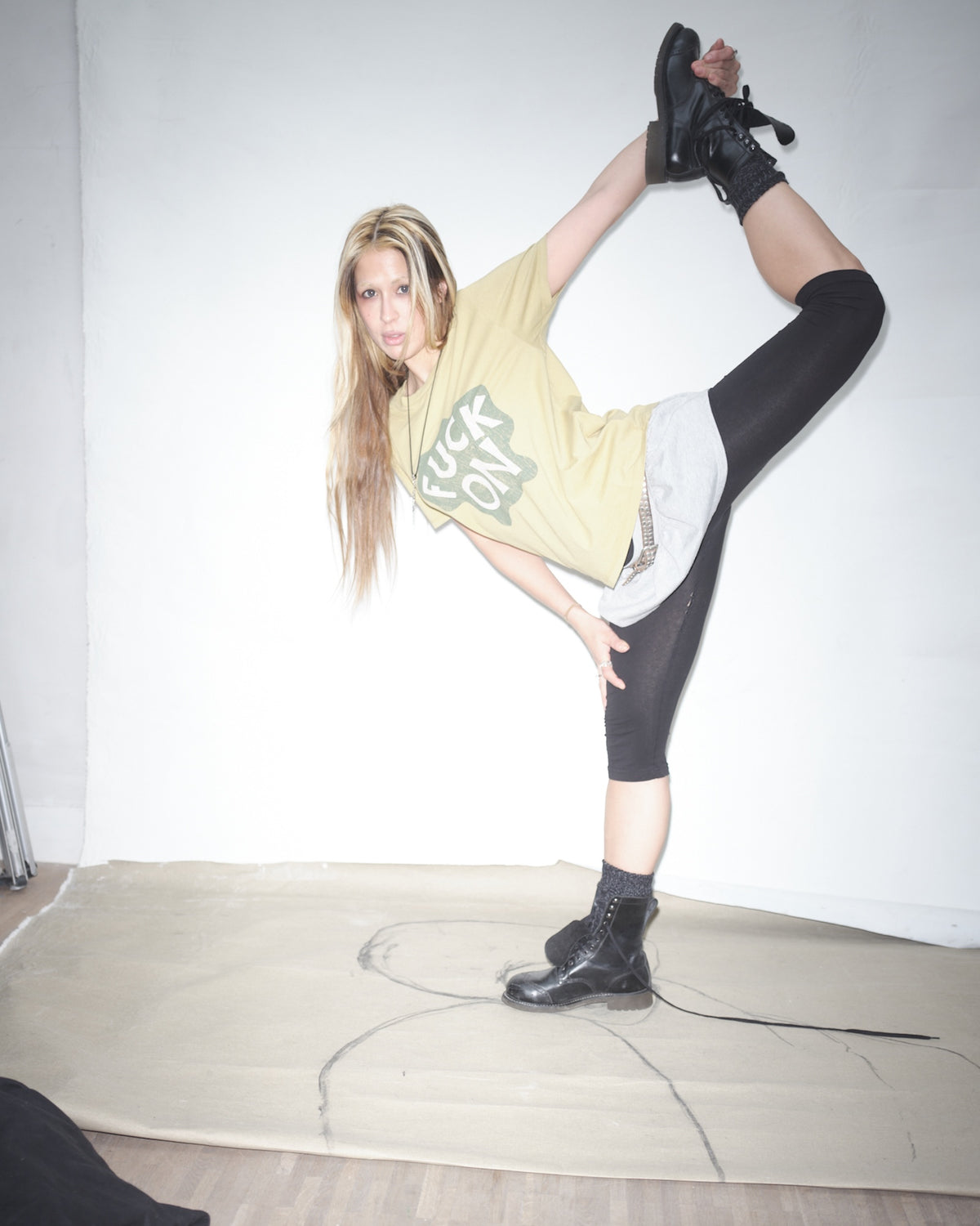 Nena Vadman in an earth Bum Society t-shirt and black leggings posing in Bum Society boots on a white background