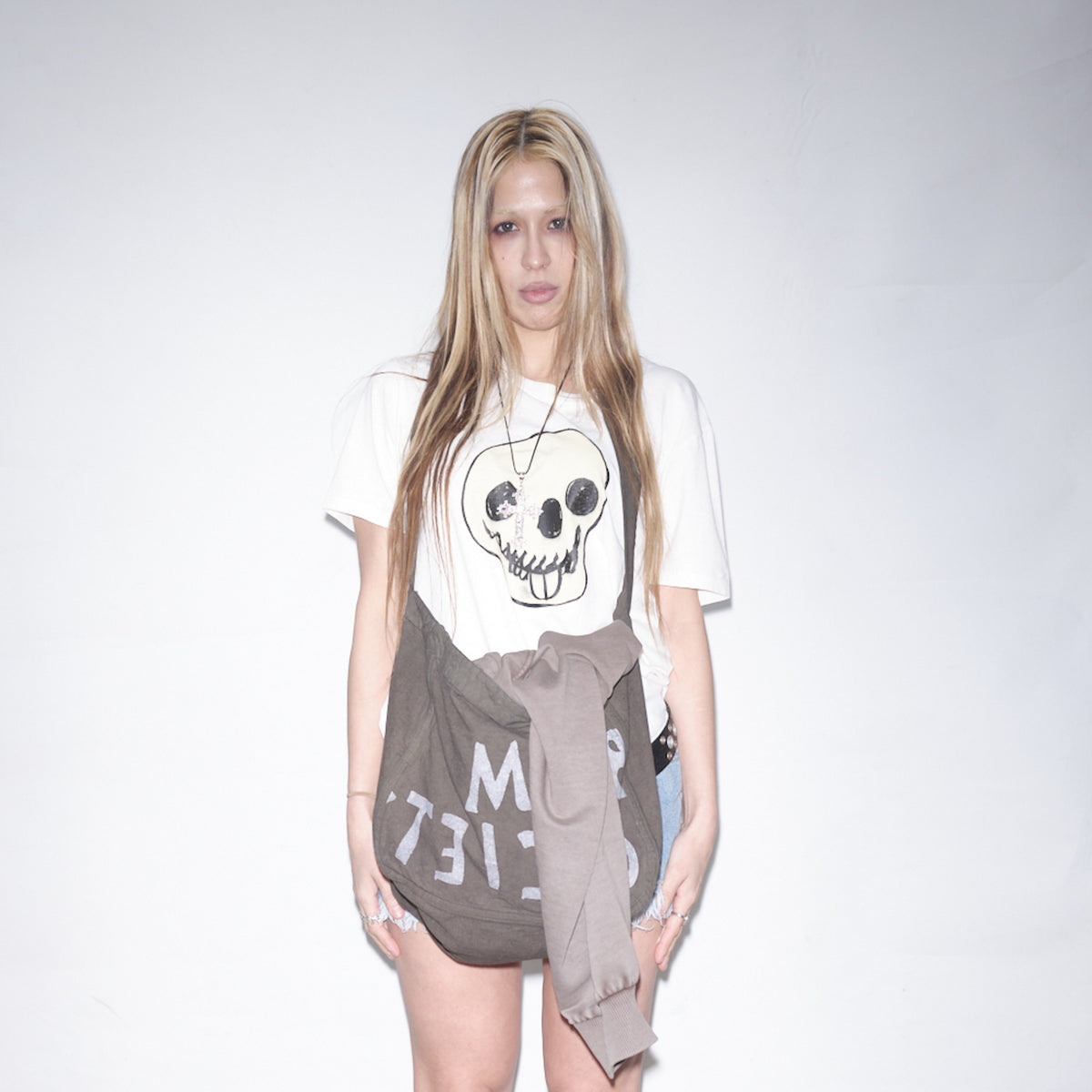 Person wearing a snow colored t-shirt with an original Jesper Waldersten artwork Happy Dead on Bum Society t-shirt and a gray skirt on a plain background color:snow