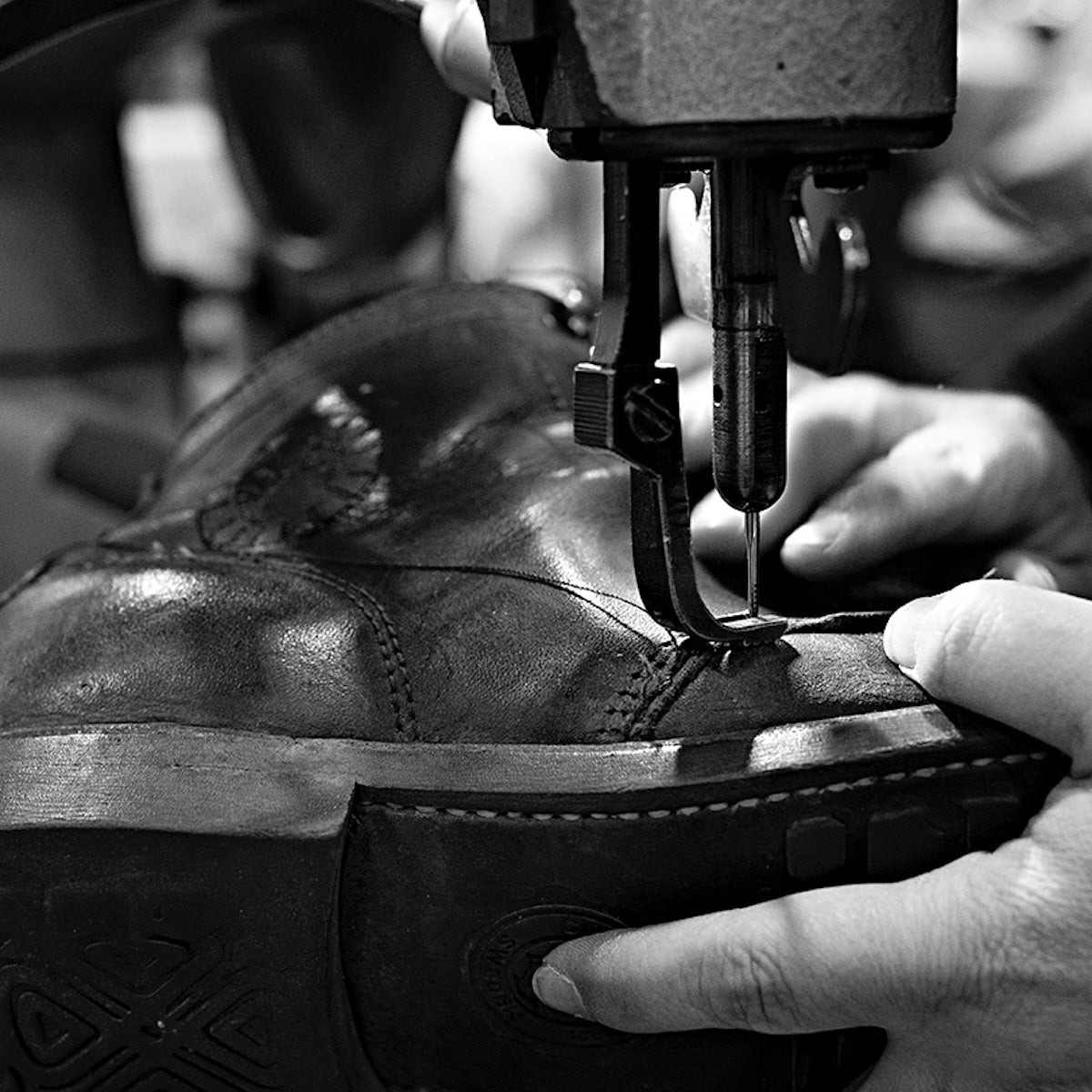 Close-up of a Bum Society leather boot being sewn with a sewing machine.