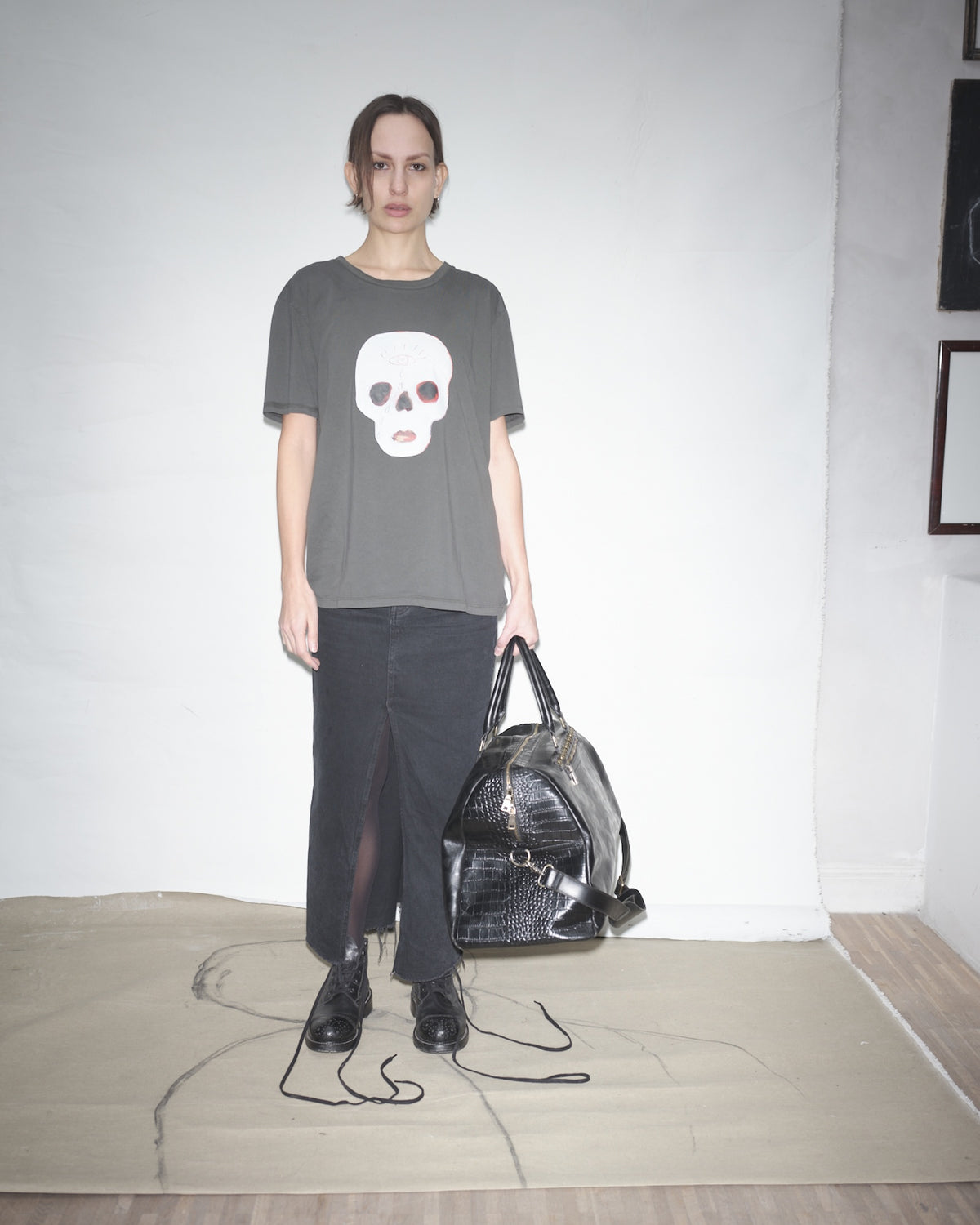 Rakel Lindgren wearing an ink Waldersten x Bum Society t-shirt, holding a black Bum Society duffle bag in a minimalistic room.