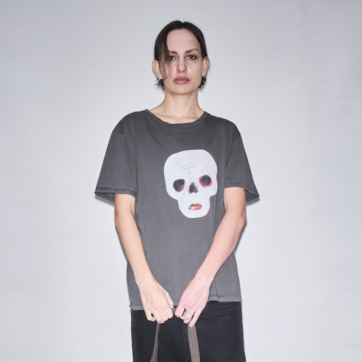 Person wearing a dark gray t-shirt with original Waldersten x Bum Society print Cry Baby color:ink