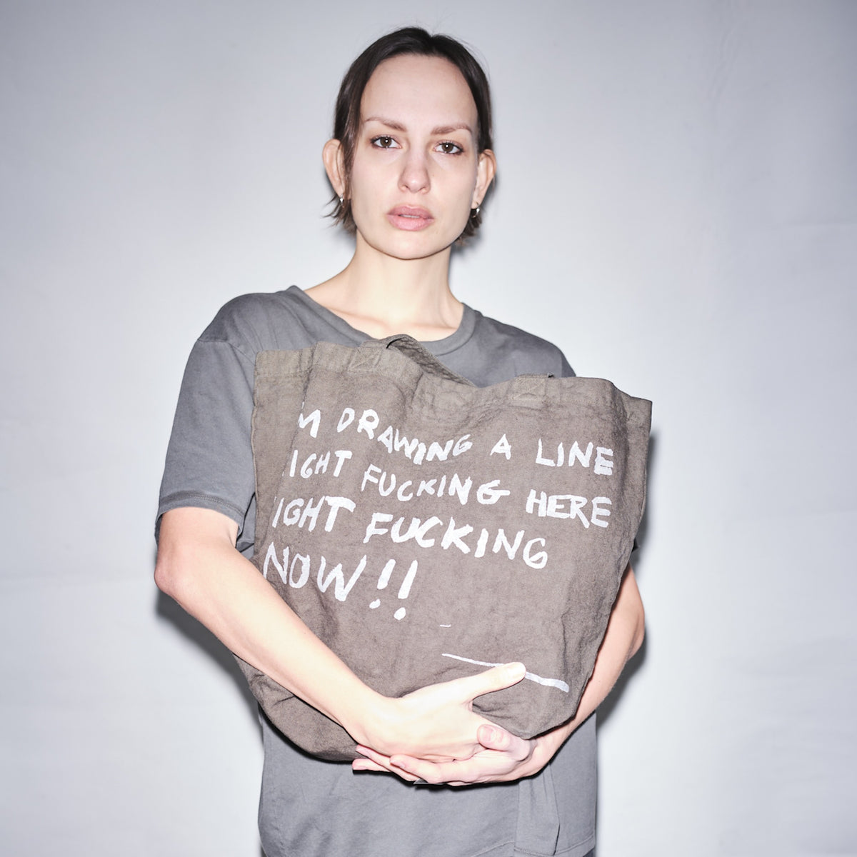 Person holding a Bum Society x Waldersten tote bag against a bright background color:ink
