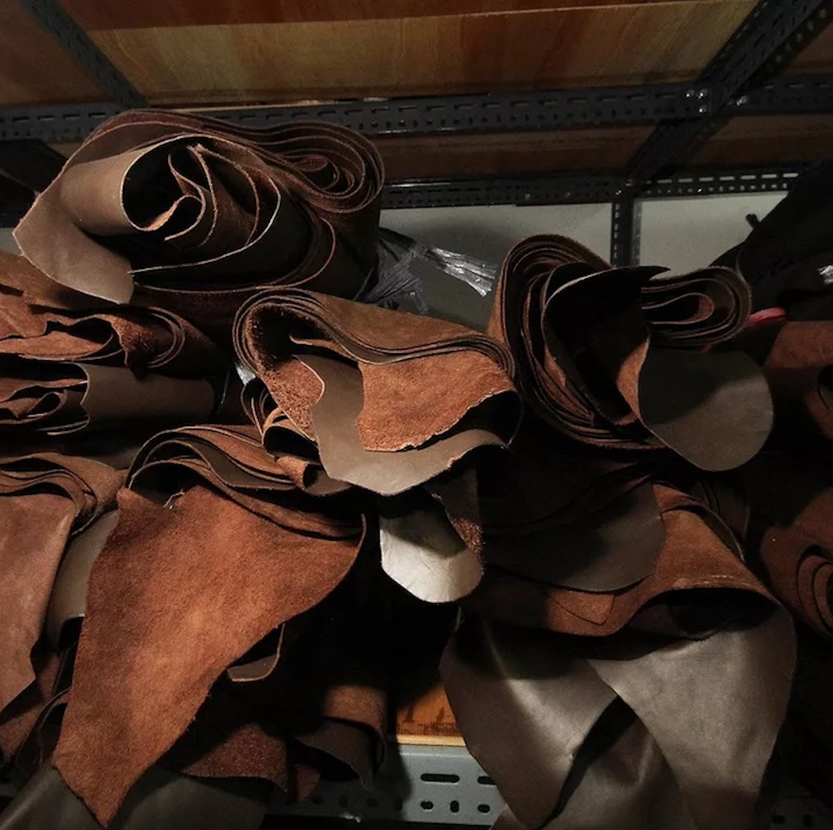 Stack of brown leather hides on a metal shelf
