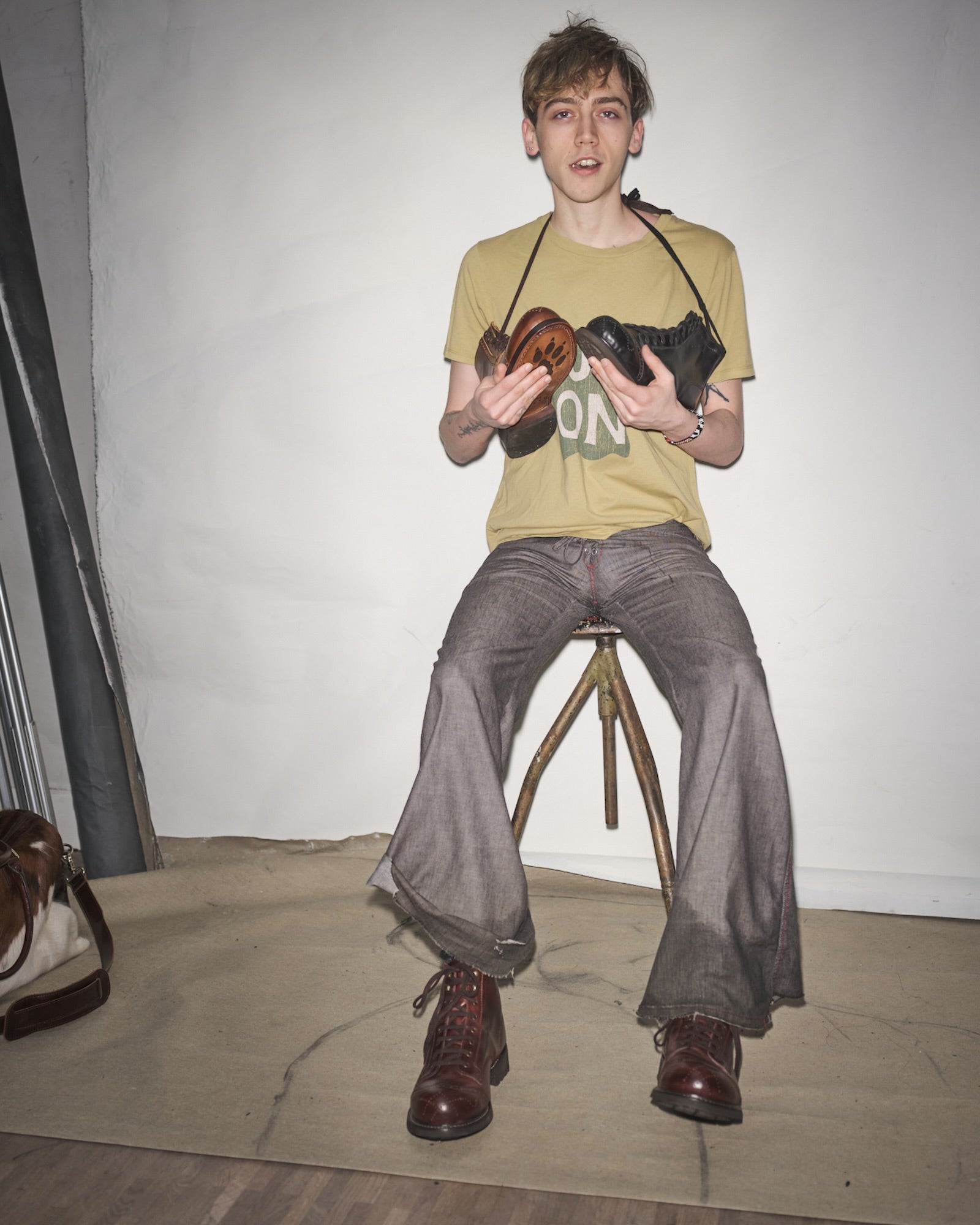 Vanja Filipovicz sitting on a stool holding two Bum Society boots against a plain background