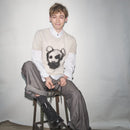 Person wearing an original Waldersten x Bum Society t-shirt Animal Boy artwork sitting on a stool against a plain background color:mud