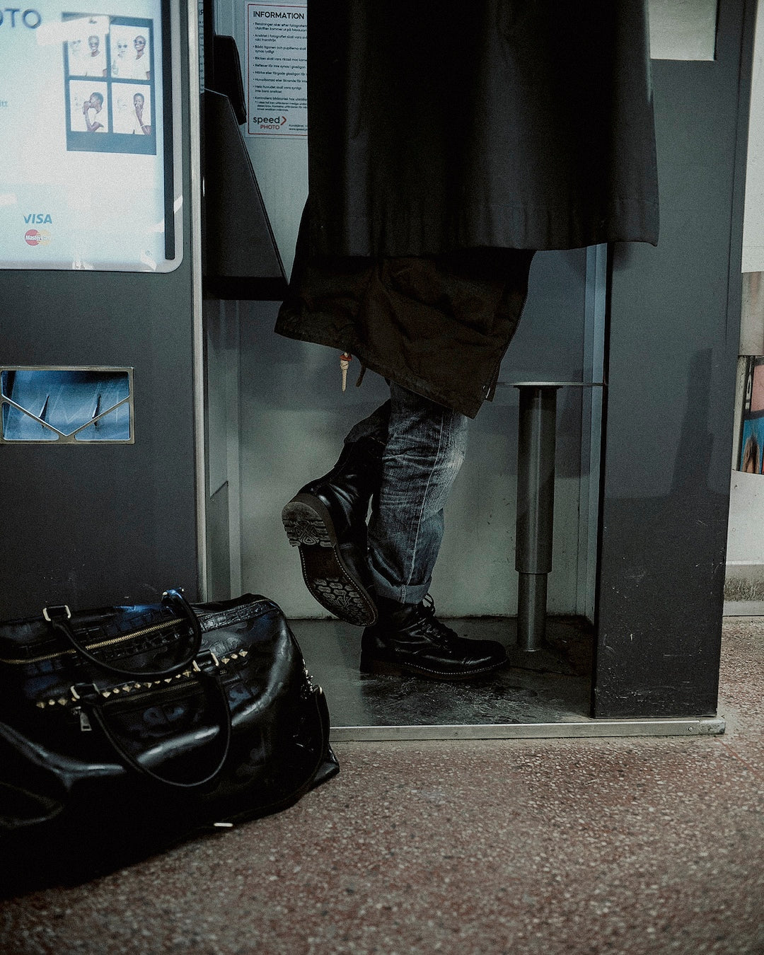 Photobooth session leaning against back wall in Bum Society boots and duffle leather bag on floor